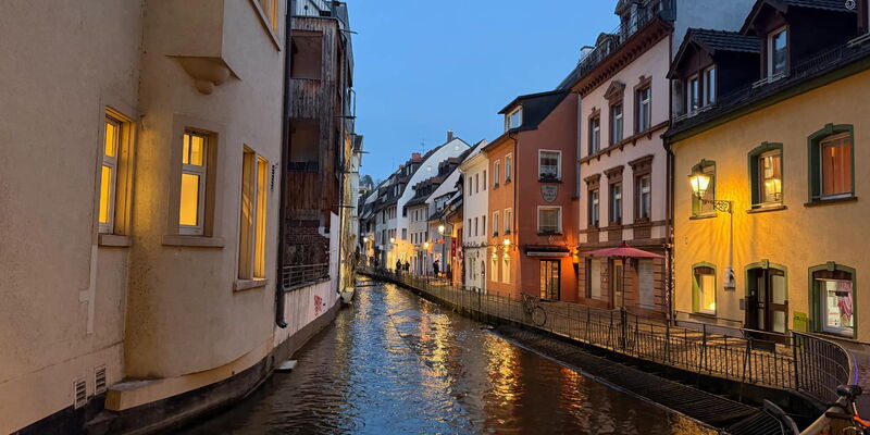 Fischerau in Freiburg bei Abenddämmerung, Häuser spiegeln sich im Gewerbekanal.