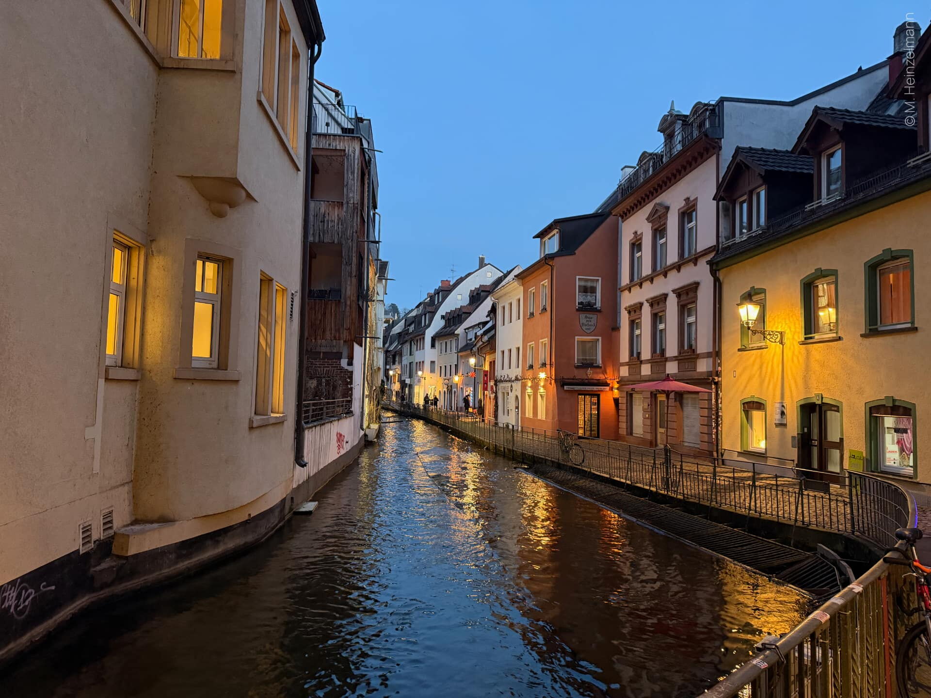 Fischerau in Freiburg bei Abenddämmerung, Häuser spiegeln sich im Gewerbekanal.
